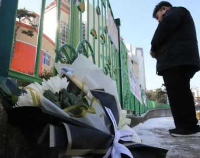 A South Korean classroom with police tape and a chalkboard in the background, symbolizing the tragic incident of a teacher arrested for fatally stabbing an eight-year-old child