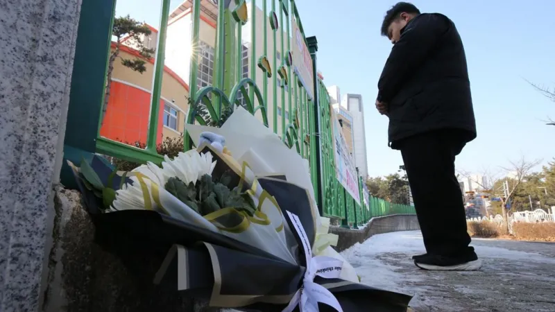 A South Korean classroom with police tape and a chalkboard in the background, symbolizing the tragic incident of a teacher arrested for fatally stabbing an eight-year-old child